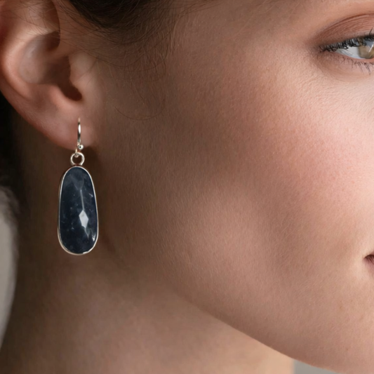 Close-up of a woman wearing raw sapphire drop earrings.